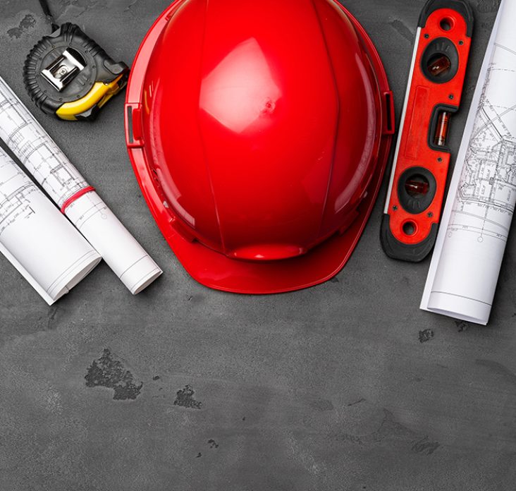 Construction worker hardhat, blueprints and .construction level, top view on wooden background