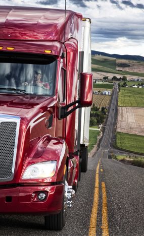 Close up view of the cab and driver of a commercial truck on the highway.